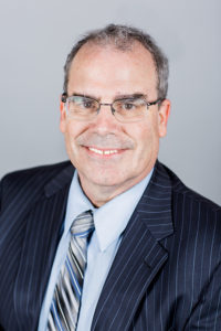 HWLF_rhines_resized Robert Hines Jr., attorney at The Hines & Wilson Law Firm, smiling in professional attire with a striped suit and tie, emphasizing expertise in personal injury and workers' compensation law.