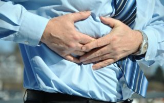 the mid section of a man wearing a dress shirt and tie grabbing at the side of his abdomen