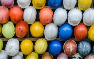 a wall of various colored hanging hard hats