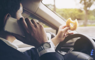 Man eating donuts while using mobile and driving car - multitasking unsafe driving concept