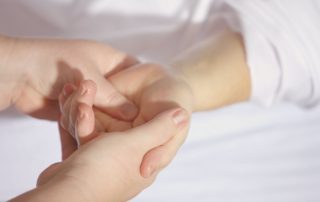 someone massaging another person's hand wearing all white