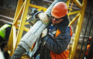 a construction worker carrying a large pile over his shoulder on a construction site