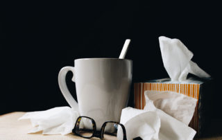 a mug, glasses, and tissues on a surface with black background