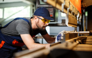 Portrait of worker near metalworking machine, steel factory background.