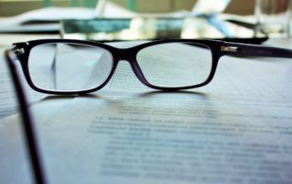 a pair of glasses sitting on top of paperwork