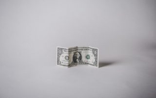 a creased dollar bill standing up on a white background