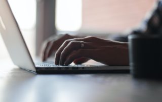 close up of man's hands typing on a laptop keyboard